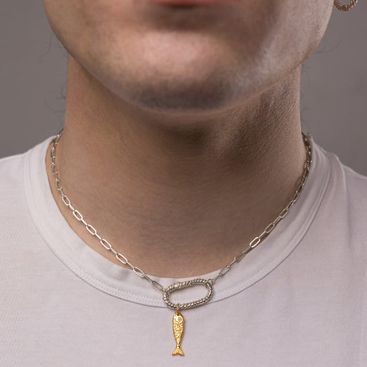 A model wearing a silver chip chain necklace with a gold fish charm