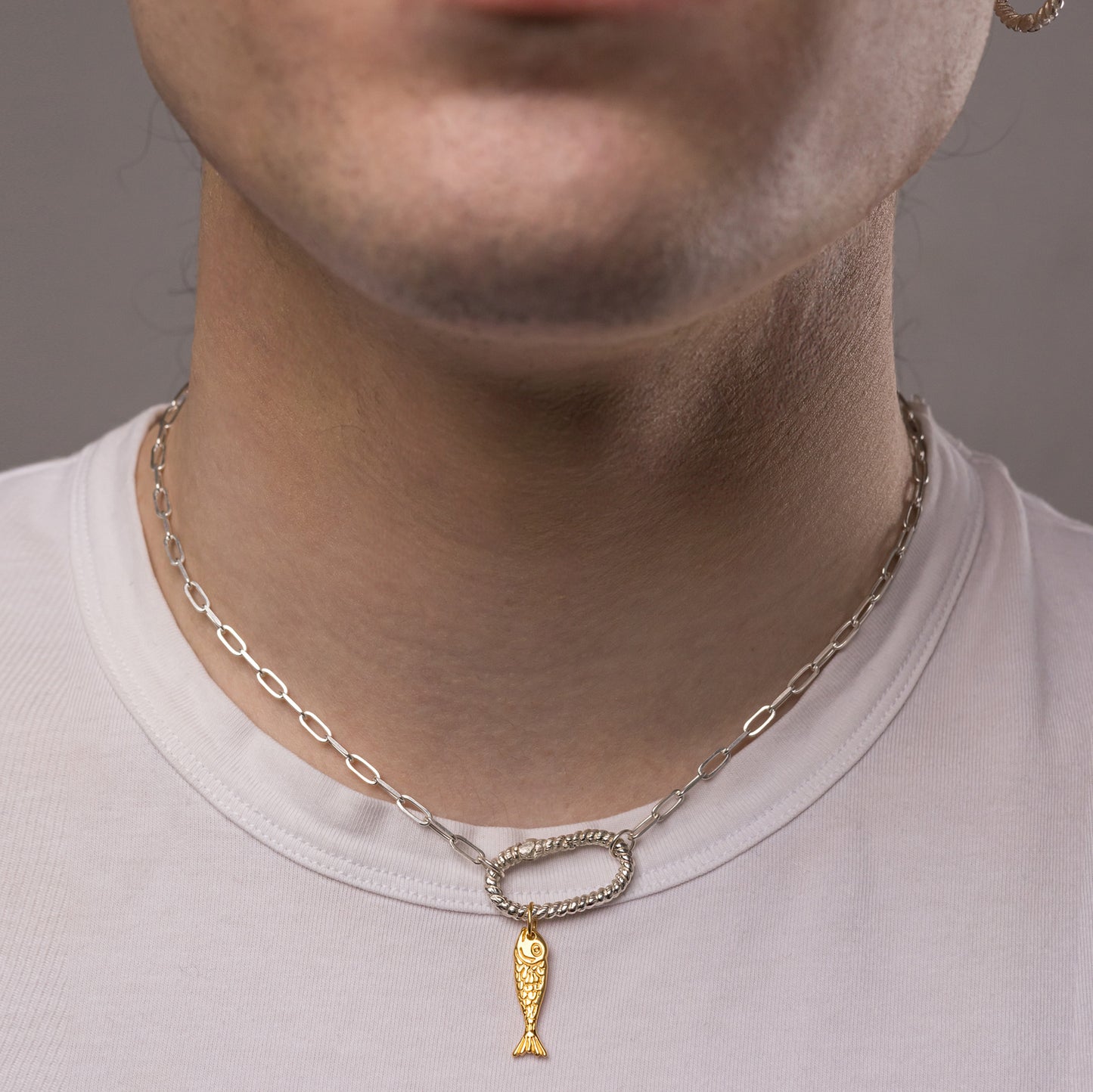 A model wearing a silver chip chain necklace with a gold fish charm