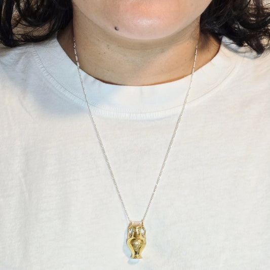 Necklace with a gold pendant worn by a person on a white background