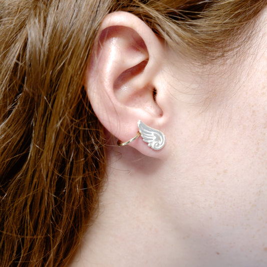 Hunt Of Hounds Arion Stud Earrings in silver. Detailed wing studs. Unisex. On model.