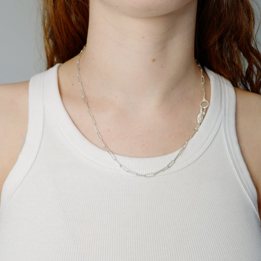 Hunt Of Hounds Serpent Hook Clip Chain Necklace. House made clip chain and signature hook. A hand holding a serpent. On model.