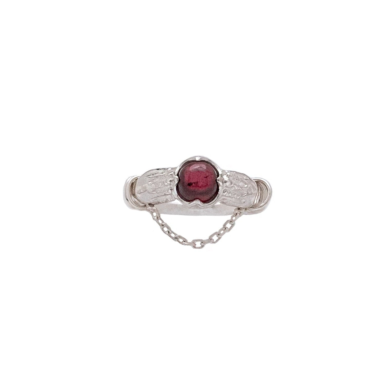 Silver ring with a red gemstone on a white background
