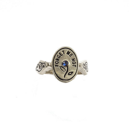 Hunt Of Hounds Forget Me Not Ring. Text surrounding a flower set with sapphire.