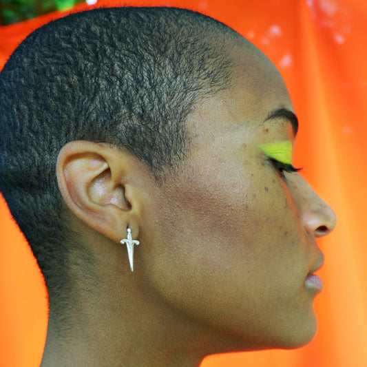 A model wearing silver dagger stud earrings