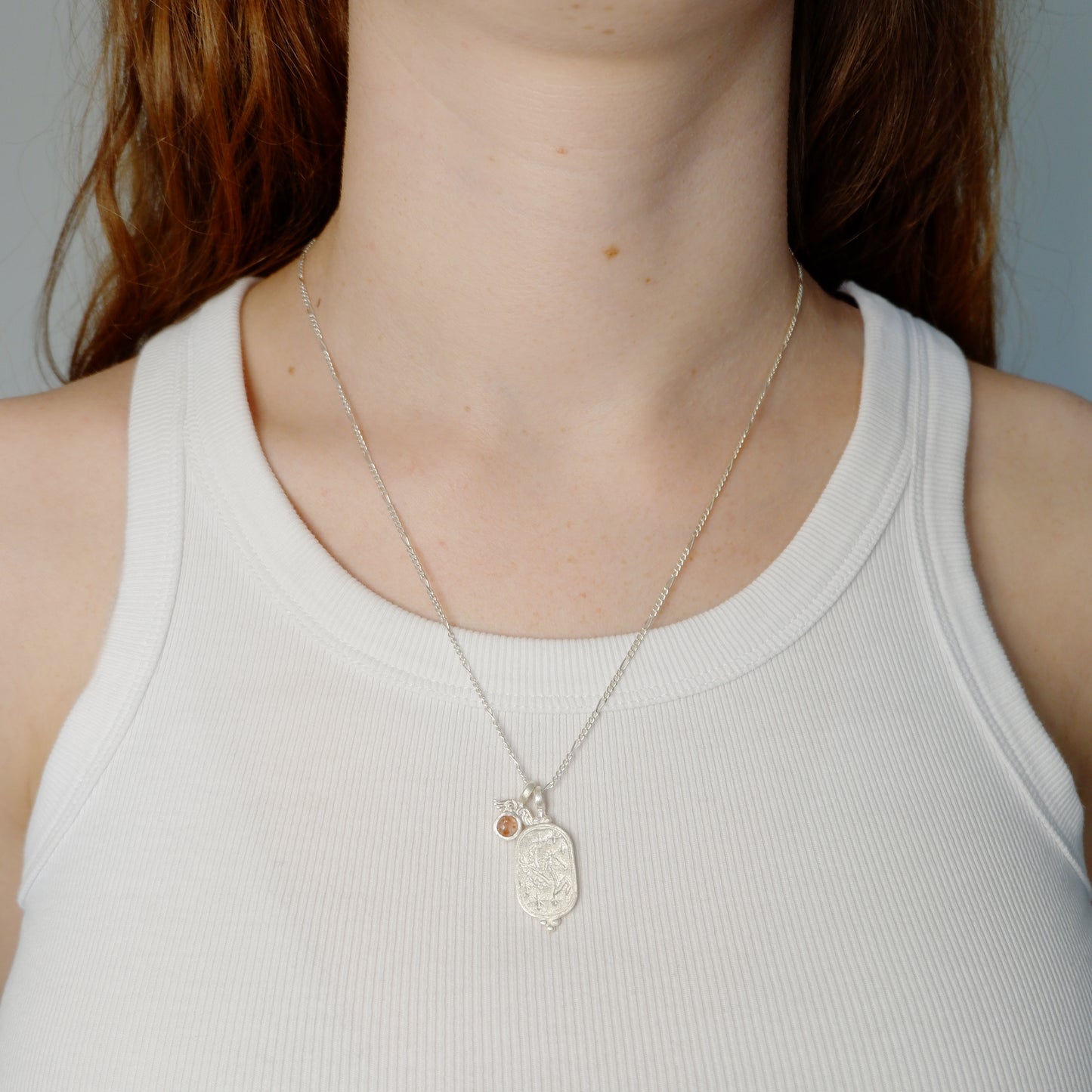 Hunt Of Hounds Pegasus Necklace. Coin pendant necklace with pegasus and stars. Sunstone charm with wings. On model.